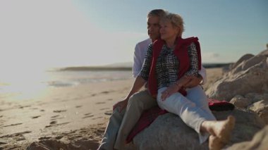 Kıdemli çift gün batımında kumsalda samimi anlar paylaşıyor.