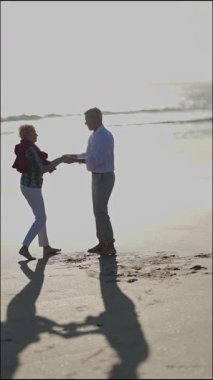 Son sınıf çifti gün batımında sahilde romantik bir dansın tadını çıkarıyor.