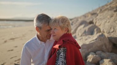 Yaşlı çift sahilde romantik bir anın tadını çıkarıyor.