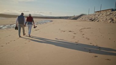 Emekli çift plajda dinlendirici bir yürüyüş yapıyor.