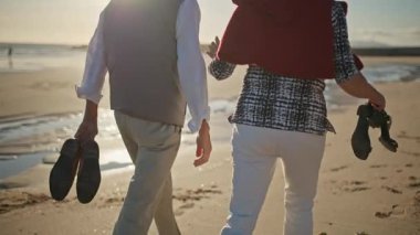 Yaşlı çift sahilde romantik bir yürüyüş yapıyor.