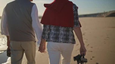 Emekli çift sahilde çıplak ayakla romantik bir yürüyüş yapıyor.