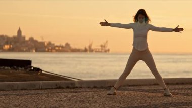 Tagus nehrinin kıyısında şafakta Tai Chi Chuan egzersizleri yapan kadın.