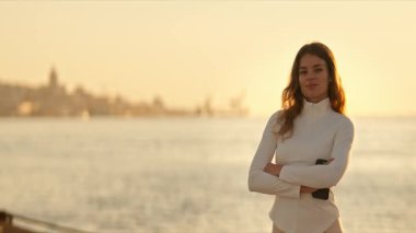 Beyaz balıkçı yaka giyen kadın deniz kenarında günbatımının tadını çıkarıyor.