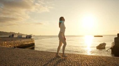 Gün batımında neşeyle dans eden enerjik bir kadın.