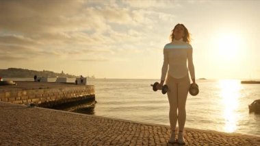 Portekiz, Lizbon 'daki tagus nehrinin kıyısında dambıllarla egzersiz yapan spor modeli.