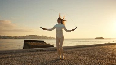 Portekiz, Lizbon 'da Tagus nehrinin yanında atlama ipiyle atlama eğitimi alan sporcu kadın.