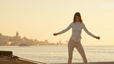 Zarif dansçı günbatımında Lisbons şehir manzarasına karşı zarif hareketler sergiliyor.