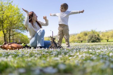 Anne ve oğul çiçek tarlasında oynuyorlar ve güneşli bir günde küçük bir şenlik ateşi yakıyorlar.