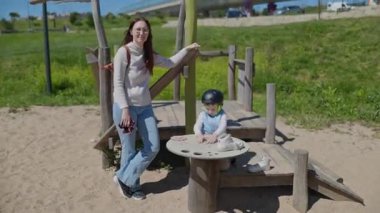 Anne ve çocuk oyun sahasında birlikte vakit geçiriyorlar.