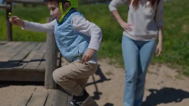 Kask takan meraklı anaokulu öğrencisi oyun masasında sarı çiçekler ve taşlar düzenliyor.