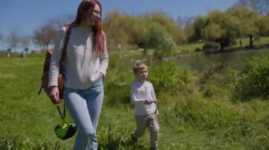 Anne ve oğlu parkta göl kenarında yürüyüş yapıyorlar.