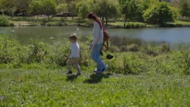 Anne ve oğlu güneşli bir günde göl kenarında keyifli bir yürüyüş yapıyorlar.