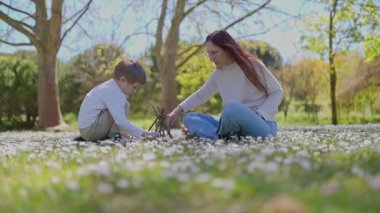 Anne ve oğlu papatya tarlasında birlikte küçük bir şenlik ateşi yakıyor.