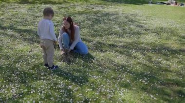 Anne ve oğul çayırda kuru dallarla küçük çadır kuruyorlar.