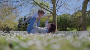 Mutlu anne ve oğul güneşli bir günde papatya tarlasında birlikte oynuyorlar.