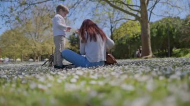 Mutlu anne ve oğul papatya tarlasında güneşli bir günün tadını çıkarıyor.