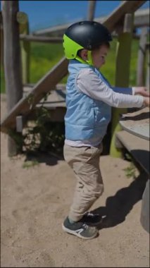 Kask takan mutlu çocuk oyun parkında kumla oynamaktan hoşlanıyor.