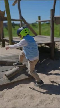 Güvenlik kaskı takan mutlu çocuk oyun alanında oynamaktan hoşlanıyor.