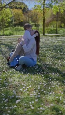 Anne ve oğlu güneşli bir günün tadını çıkarıyor, çimlerin üzerinde uzanıp birlikte oynuyorlar.