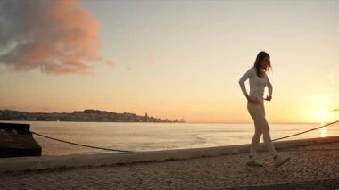 Lisbon, Portekiz 'deki tagus nehrinin yakınındaki kaldırımda ısınan sporcu kadın.