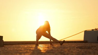 Altın saat boyunca çatıda yoga yapan bir kadın.