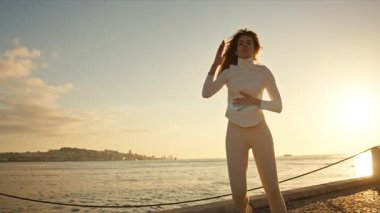 Zarif dansçı günbatımında nehrin kenarında özgürlük ve yaratıcılığı kucaklayarak çağdaş hareketler yapar.