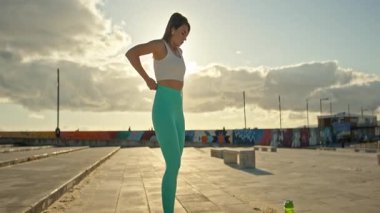 Genç, sportif kadın gün batımında esneme egzersizleri yapıyor.