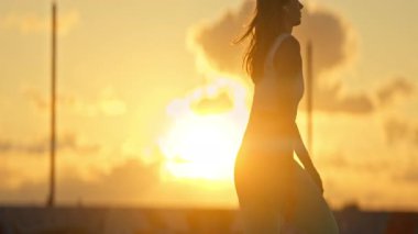 Genç sporcu kadın altın saat gün batımında koşuyor.