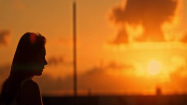 Canlı bir günbatımında zarif hareketler yapan bir bayan atletin silueti.