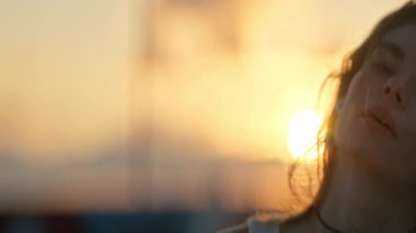 Gün batımında kablosuz kulaklıklarla müzik dinleyen genç bir kadın.