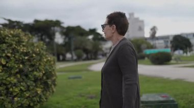 Kıdemli kadın parkta rahatça dolaşmaktan, doğayla etkileşimden ve manzaranın tadını çıkarmaktan hoşlanır.