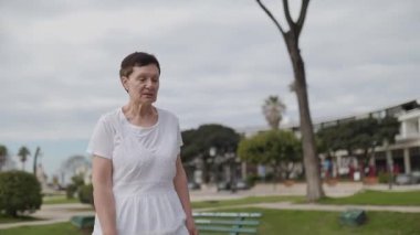 Yaşlı kadın parkta yürümekten hoşlanıyor, sağlıklı yaşlanma ve aktif yaşam tarzını teşvik ediyor.