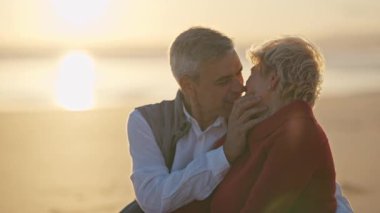 Sevecen son sınıf çifti güzel bir günbatımında sahilde romantik bir anın tadını çıkarıyor.