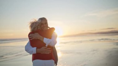 Yaşlı çift sahilde romantik bir anın tadını çıkarıyor.