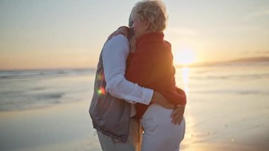 Kıdemli çift gün batımında sahilde romantik bir anın tadını çıkarıyor.