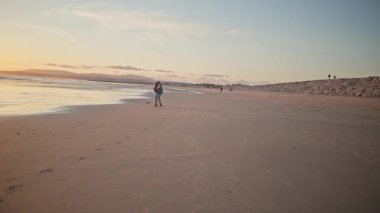 Gün batımında sahilde koşan bir kadın, telefoto.