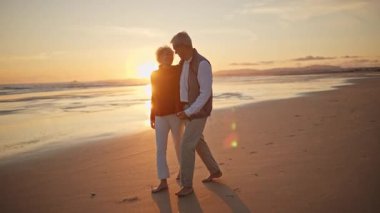 Son sınıf çifti gün batımında sahilde romantik bir yürüyüş yapıyor.