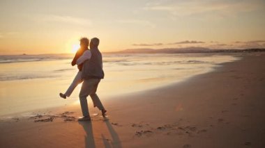 Kıdemli çift gün batımında sahilde eğleniyor.