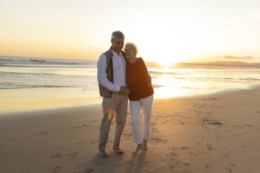 Gün batımında sahilde çıplak ayakla yürürken sarılıp el ele tutuşan yaşlı bir çift emeklilik sırasında romantik bir anın tadını çıkarıyor.