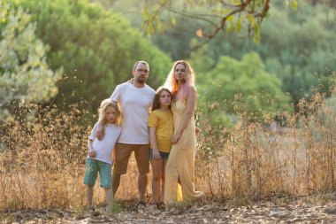 İki kızı olan bir aile, doğa koruma alanında birlikte poz veriyor.