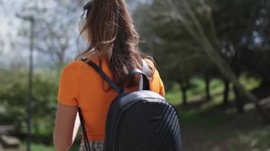 Turist akıllı telefonuyla fotoğraf çekiyor ve şehir parkında müzik dinliyor.