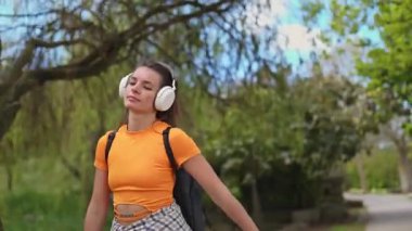 Sıradan bir genç kadın, yeşil bir parkta rahatlama yürüyüşü sırasında kulaklıkla müzik dinlemekten hoşlanır.