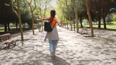 Kaygısız öğrenci, kulaklık takıyor, dans ediyor ve güneşli bir parkta müzik dinliyor.