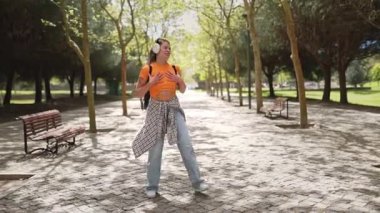 Kulaklıkla müzik dinleyen ve parkta dans eden mutlu bir öğrenci.
