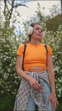 Parkta müziği seven, kulaklık takan ve dans eden bir kadın.