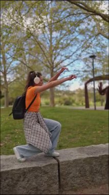 Tasasız öğrenci, parkta alçak bir duvarda yürürken kulaklıkla müzik dinlemekten zevk alır.