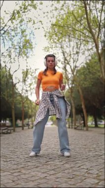 Enerjik bir kadın parkta müzik ve dans etmekten hoşlanıyor.