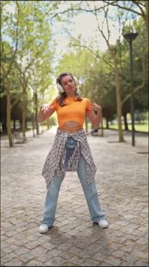 Parkta kulaklıkla dans eden genç bir kadın.