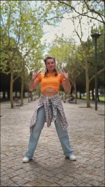 Enerjik dansçı hareketlerini canlı bir park ortamında sergiliyor.